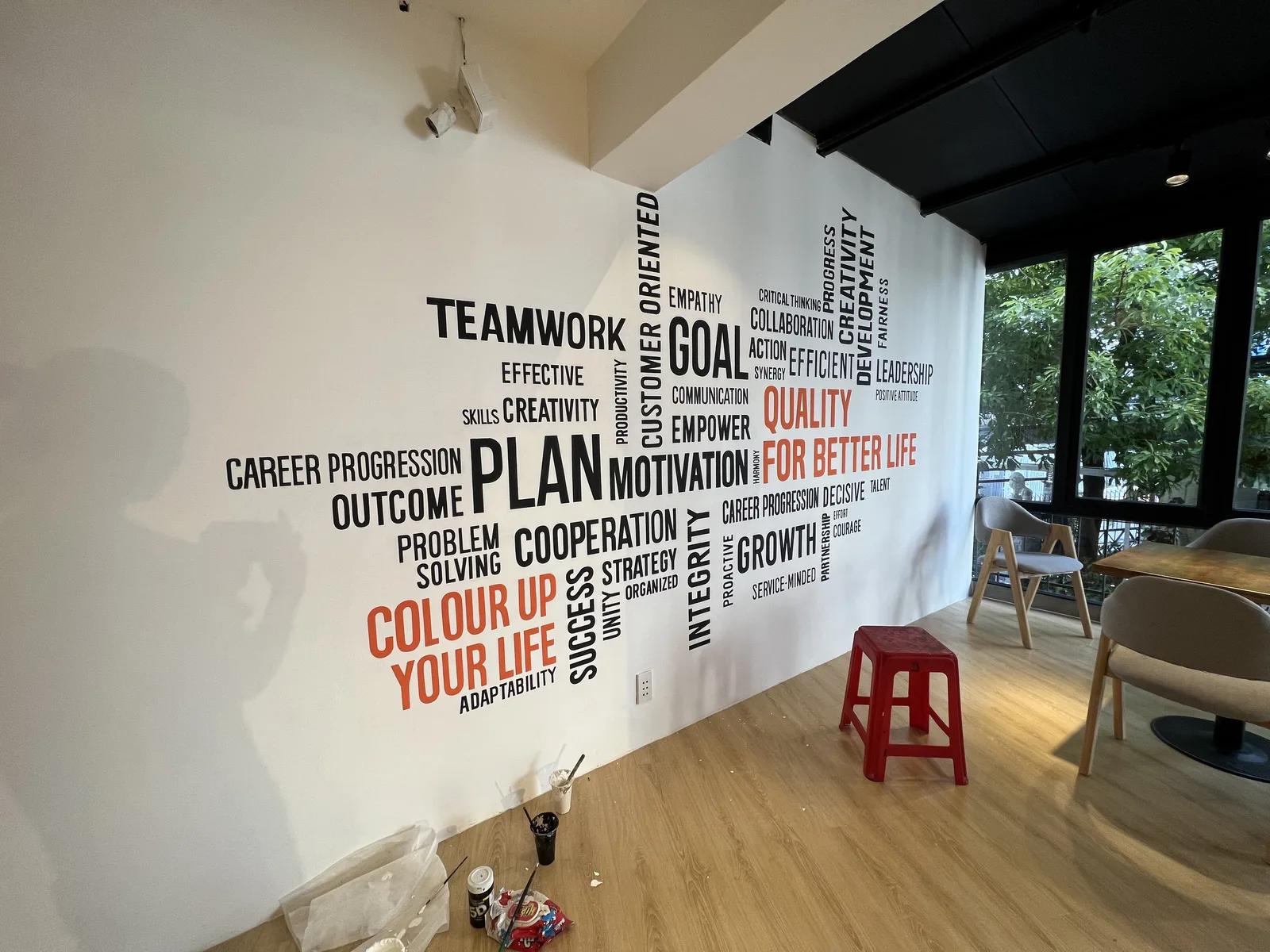 Giá vẽ tranh tường 1m2 dạng chữ typography đen cam trên tường trắng văn phòng