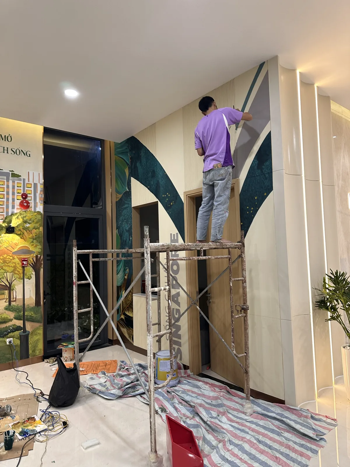 Họa sĩ Thái Luận Art đứng giàn giáo vẽ chi tiết tranh tường nhà mẫu