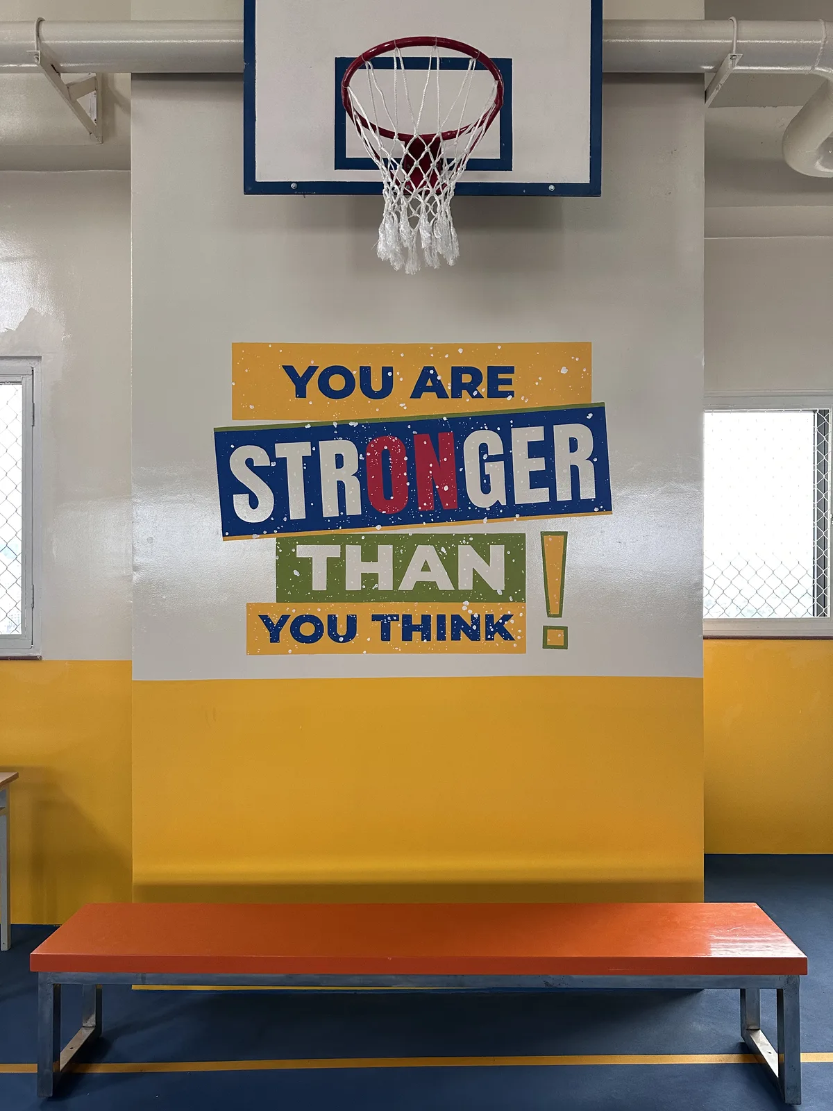 Vẽ tranh tường chữ You are stronger than you think ở sân bóng rổ trong nhà