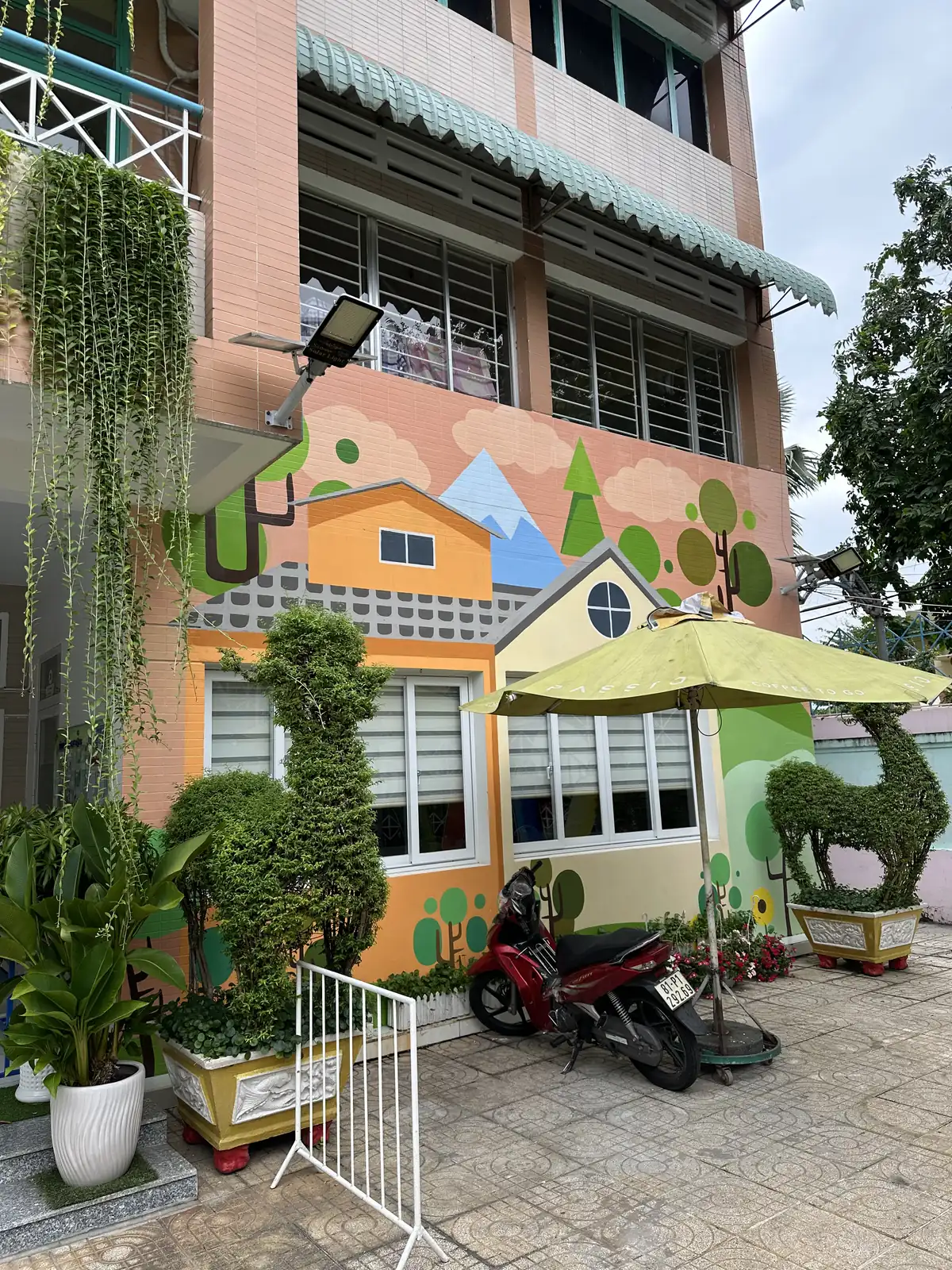 Vẽ tranh tường trường mầm non: ngôi nhà màu cam mái hồng ở mặt tiền
